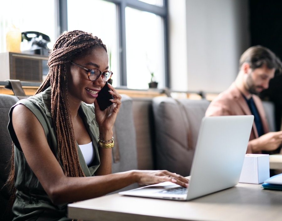 woman talking on phone while looking through laptop